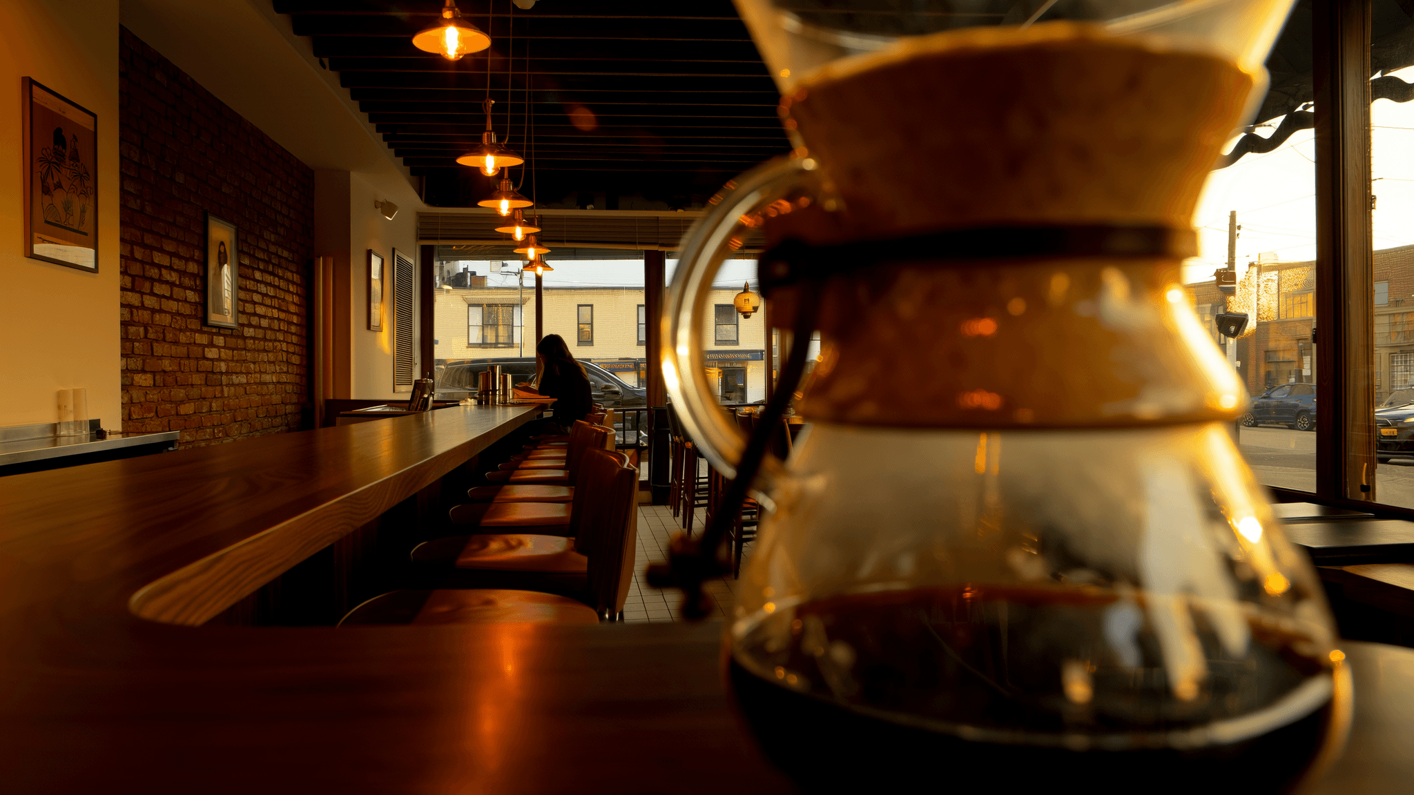 Chemex carafe in foreground with the bar stretching into warm amber depth